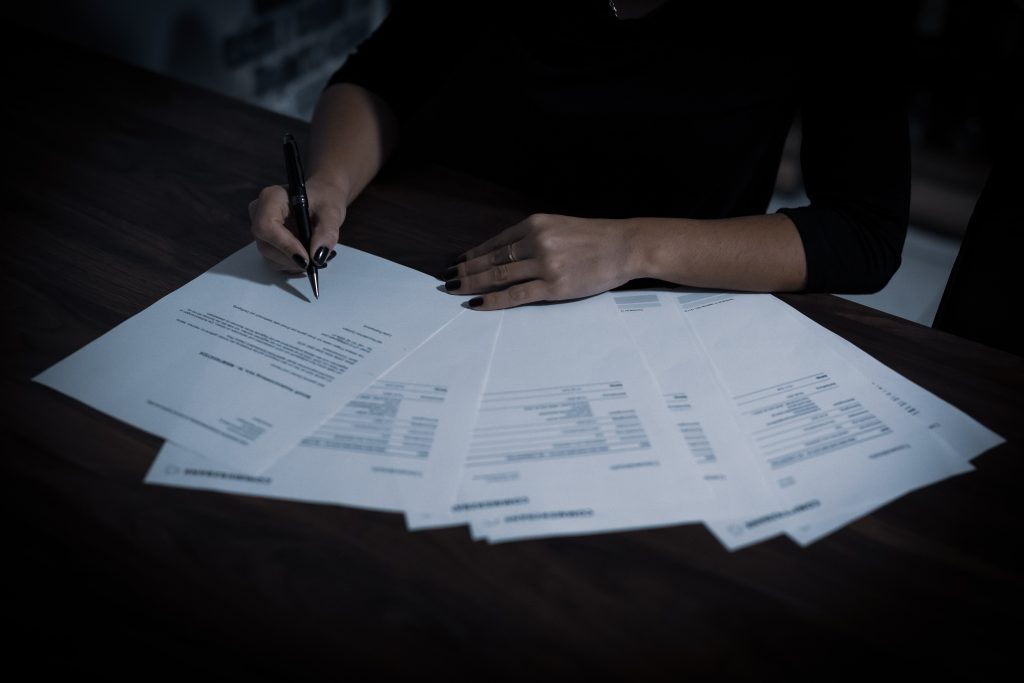 kobieta przy biurku sprawdza dokumenty - weryfikacja obowiązku podatkowego w Niemczech